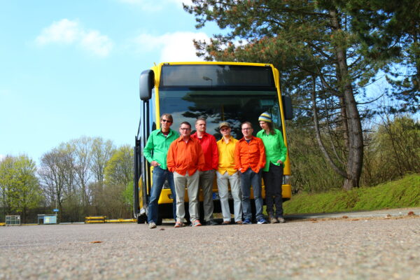 6 Mitglieder der Band in bunten Hemden vor einem Bus .