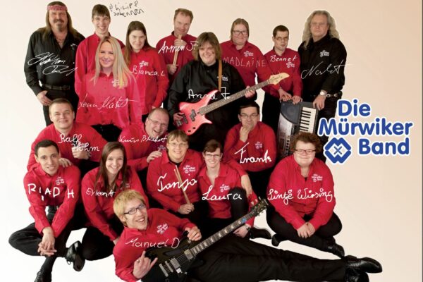 Gruppenbild aller Bandmitglieder in roten und schwarzen Band-Shirts