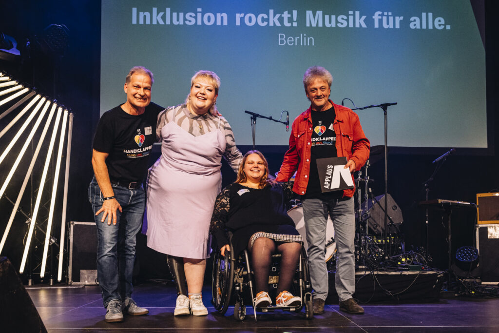 Foto von vier glücklichen Menschen auf einer Bühne.