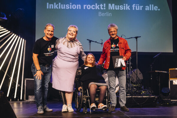 Foto von vier glücklichen Menschen auf einer Bühne.