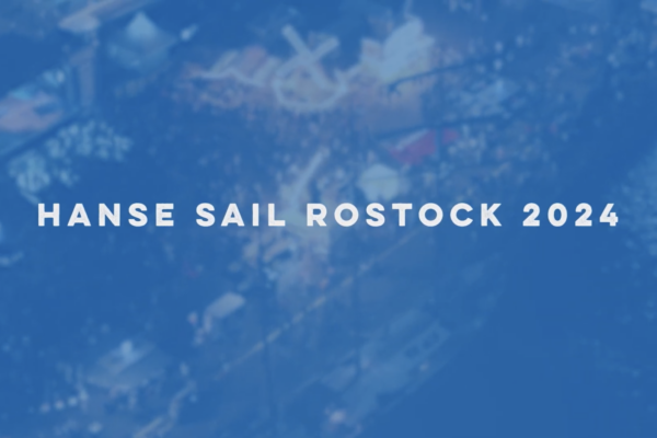 Grafik mit Schrift im Vordergrund "Hanse Sail Rostock 2024", im Hintergrund sehr unscharf ein Foto mit Menschenmenge