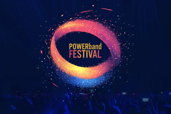 Logo Powerband Festival in einem großen Saal an die Wand geworfen, darunter eine nicht im Einzelnen zu erkennende Menschenmenge.
