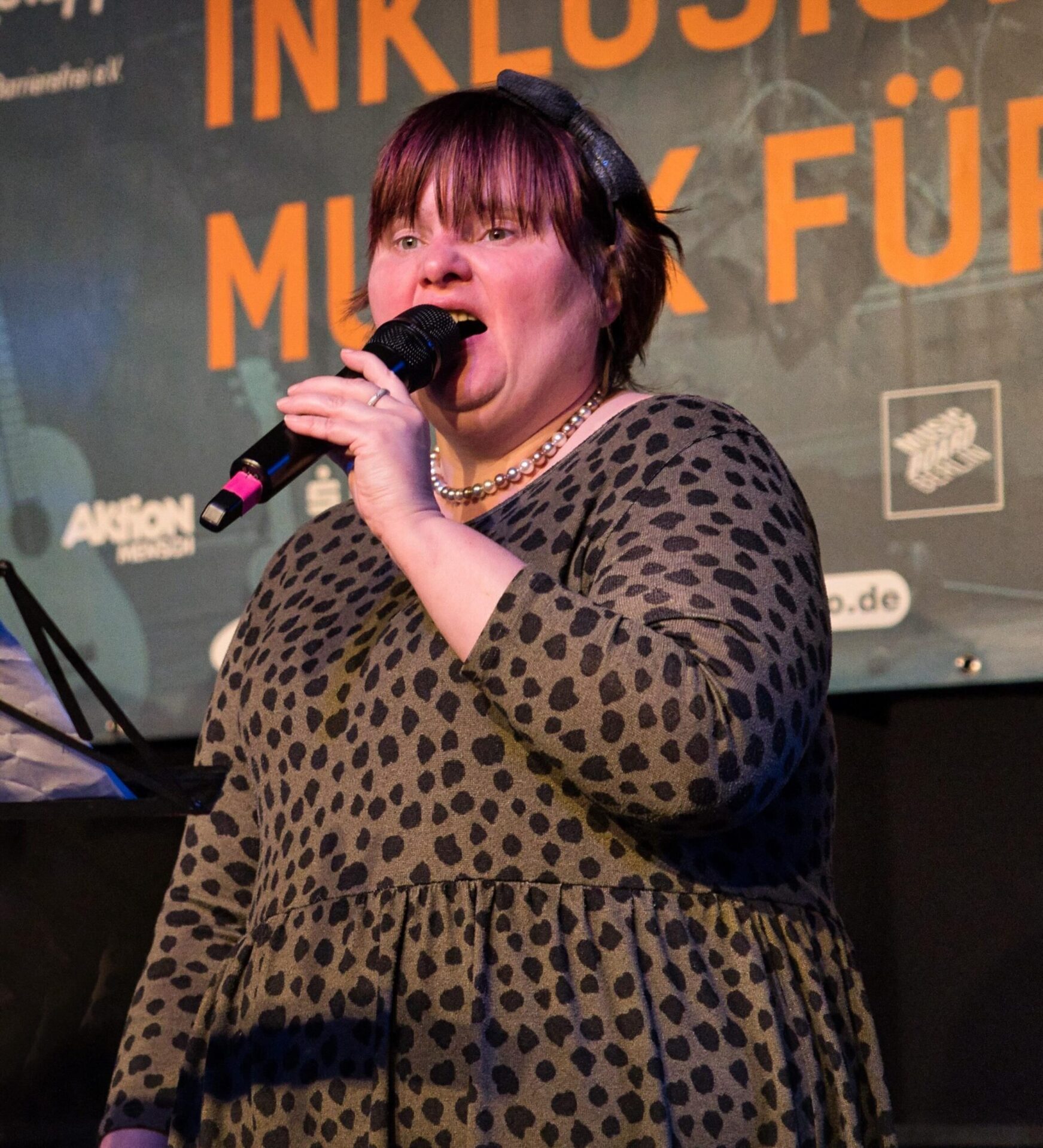 Buntfoto von einer Sängerin auf der Bühne, die in ein Handmikrofon singt.