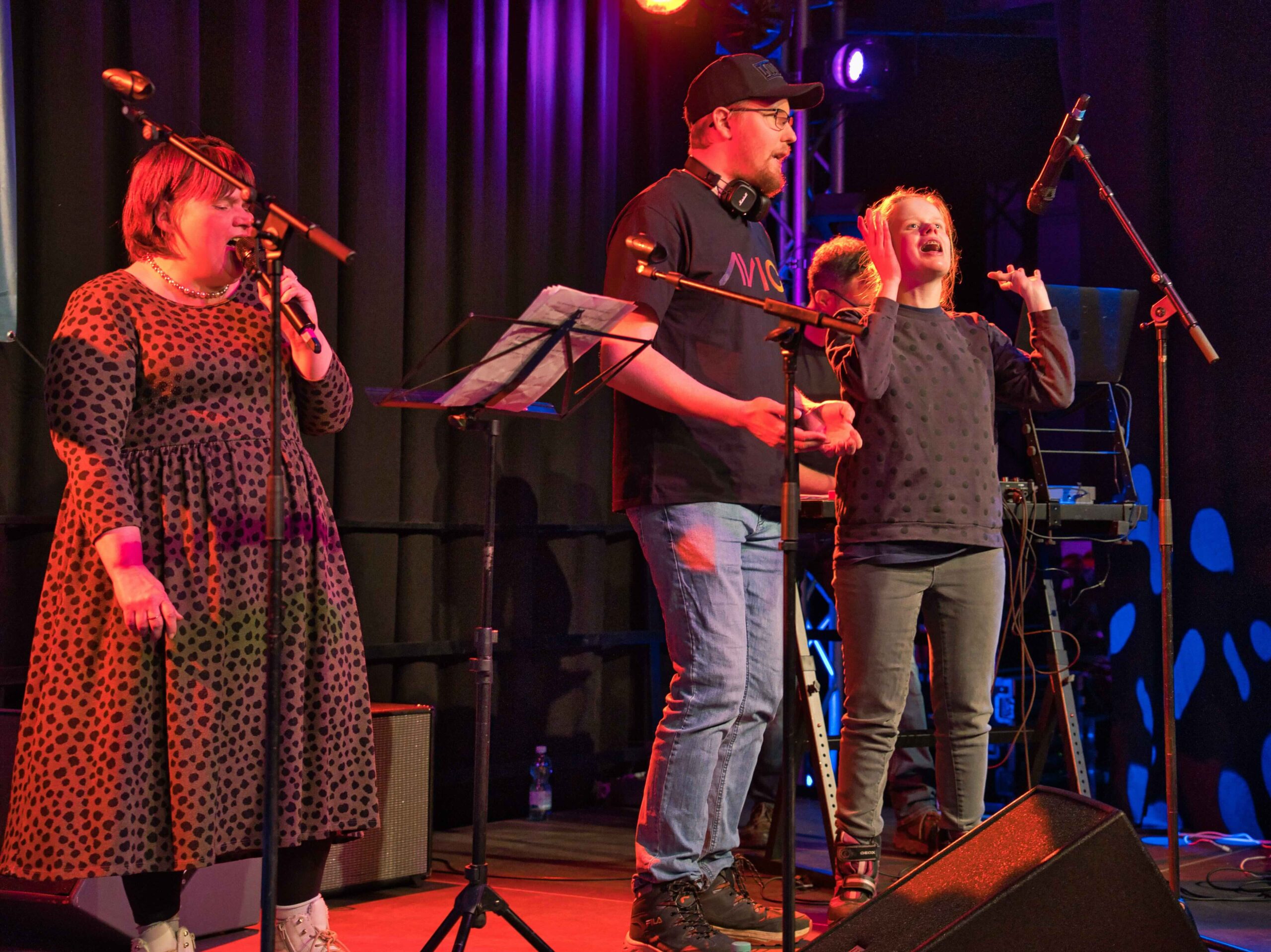 Buntfoto von vier Menschen die auf der Bühne stehen und begeistert singen.